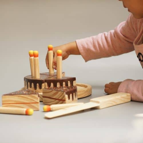 girl playing with chocolate wooden cake toy