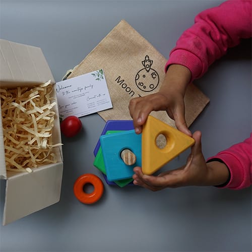 baby playing with colorful neemwood toys with box